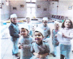 Senioren und Kinder in Schürzen beim Backworkshop